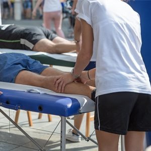 Sports rehabilitator massaging athletes leg before competing in a race